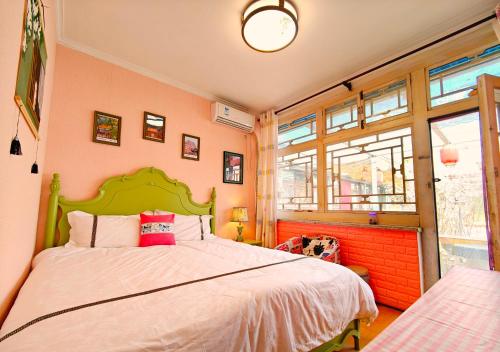 a bedroom with a large bed with a green headboard at Beijing Badaling Great Wall Caos Courtyard Hostel 1Private english tour guide 2Pick up&Drof off &landmark visiting serivice3Very near to Badaling Great Wall4Offer free beijing travel guide5Traditonal Chinese courtyard in Yanqing