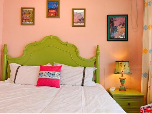 a bed with a green headboard and pink walls at Beijing Badaling Great Wall Caos Courtyard Hostel 1Private english tour guide 2Pick up&Drof off &landmark visiting serivice3Very near to Badaling Great Wall4Offer free beijing travel guide5Traditonal Chinese courtyard in Yanqing