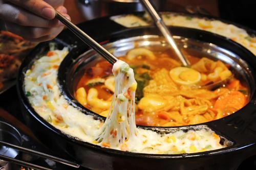 a person holding a spoon in a bowl of food at HN ETH Vinhomes D'capitale Resident - Tran Duy Hung St in Hanoi
