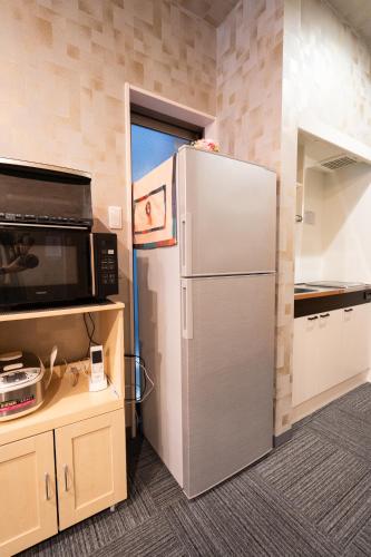 a kitchen with a refrigerator and a microwave at 福楽亭 in Minami-sotoborichō