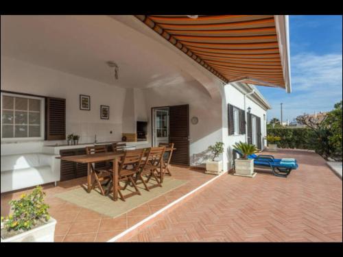 a patio with a table and chairs and a kitchen at Villa Vilamar in Porches