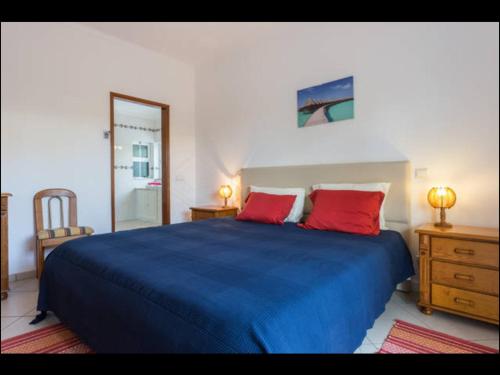 een slaapkamer met een blauw bed met 2 rode kussens bij Villa Vilamar in Porches