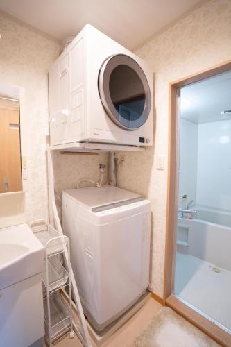 a washer and dryer in a bathroom with a microwave at 福楽亭 in Minami-sotoborichō