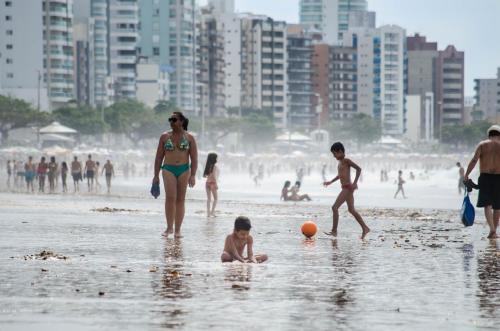 a group of people playing in the water at the beach at CONFORTO IMBATIVEL - 25 metros do MAR - 2 Quartos com AR CONDICIONADOS SPLIT, Air Fryer, WI-FI, Disney Plus, Star Plus, HBO Max, Guarda Sol, Cadeiras de Praia e Caixa Térmica - 8 pessoas com Muito Conforto - Melhor Localização! in Guarapari