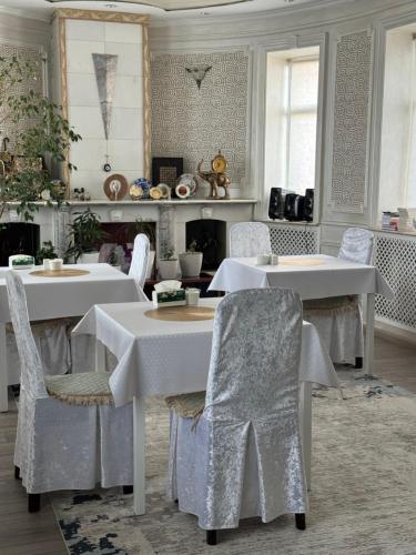 a dining room with white tables and chairs at Ricco guest house in Bishkek