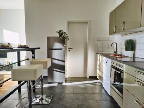 a kitchen with a stainless steel refrigerator and a table at Modernes Loft-Erlebnis mit Fitnessbereich & Heimkino in Magdeburg