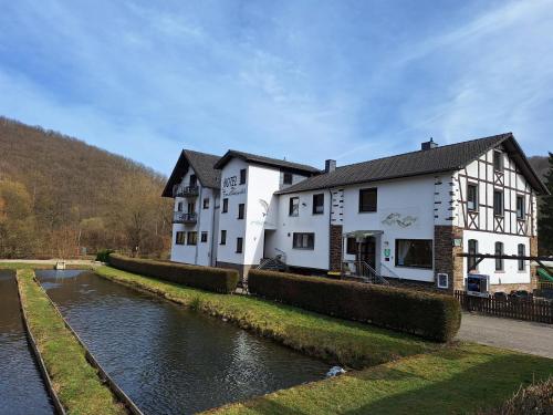 a couple of white buildings next to a river at Hotel | Restaurant | Forellenzucht in Burgen