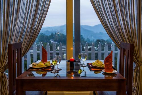a table with two plates of food and wine glasses at Villa Perpetua in Bandarawela