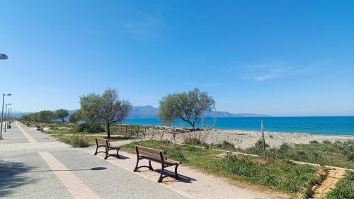 two benches sitting on a sidewalk near the beach at Relax Private Pool House in Maleme