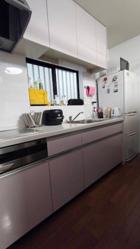a kitchen with white cabinets and a white refrigerator at エアポートマジカ in Toyonaka