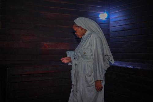 a woman dressed in white standing next to a brick wall at Nefaland Hotel in Dar es Salaam