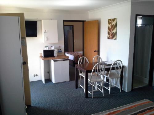 a small room with a table and chairs and a kitchen at Hideaway Motor Inn in Armidale