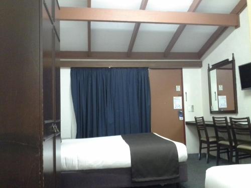 a bedroom with a bed with a blue curtain at Hideaway Motor Inn in Armidale