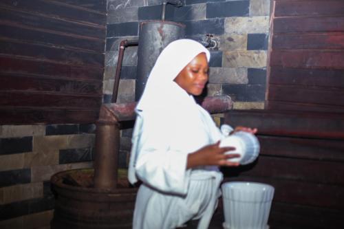 a woman in white is holding a bucket at Nefaland Hotel in Dar es Salaam