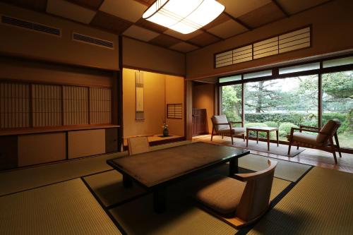 a living room with a table and chairs and windows at Monjusou Shourotei in Miyazu