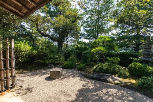 a garden with a bench and trees and bushes at Monjusou Shourotei in Miyazu