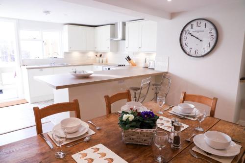 a kitchen with a table and a clock on the wall at Beautifully refurbished 3 bedroom cottage in Ashdon