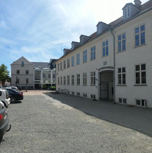 a large white building with cars parked in a parking lot at Princessen på ærten in Odense