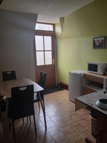 une cuisine avec une table et des chaises et un micro-ondes dans l'établissement La Bergeronnette Le Buisson, à La Chapelle-Saint-André