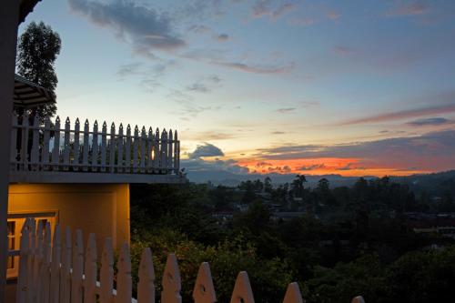 a fence in front of a house with a sunset at Villa Perpetua in Bandarawela