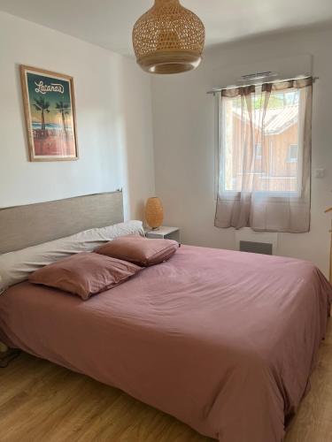 une chambre avec un grand lit avec une couverture rose dans l'établissement Villa neuve 300 m plage sud 3 chambres, à Lacanau