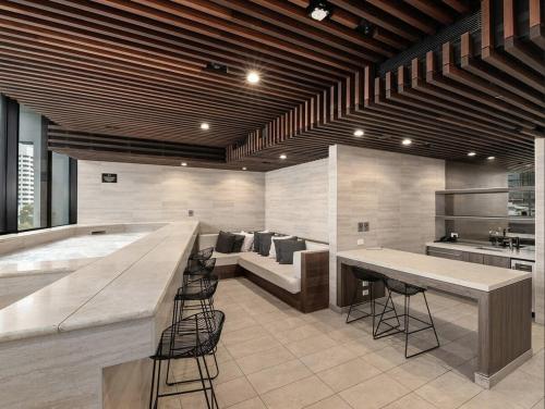 a kitchen with a large bar with chairs and a couch at Magical Sunset SkyView BEST location in Brisbane in Brisbane