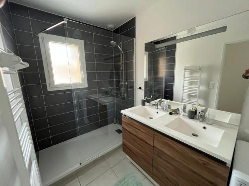 une salle de bain avec un lavabo, une douche et un miroir dans l'établissement Villa neuve 300 m plage sud 3 chambres, à Lacanau