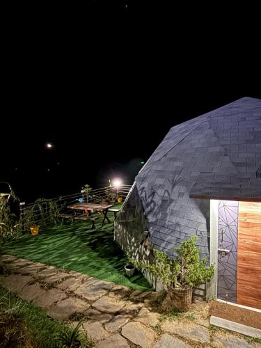 a black dome house at night with a picnic table at The Soul Stroll Cottages Retreat in Mukteswar