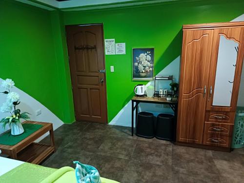 a green room with a desk and a cabinet at MilVir Tourist INN in El Nido