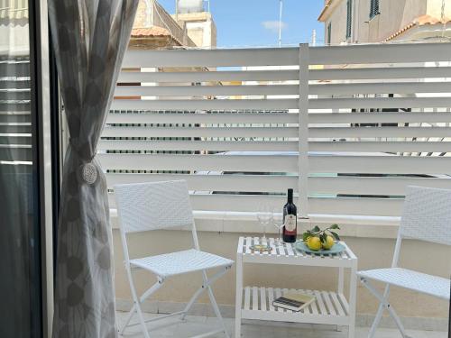 a balcony with two chairs and a table with a bottle of wine at Sunlands 50 meters from the sandy beach with wifi in Avola