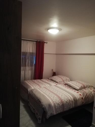 une chambre avec un lit avec un rideau rouge dans l'établissement Gîte au coeur d'un joli village de Seine et Marne, à Boulancourt