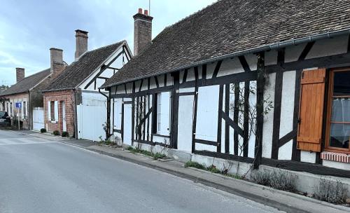 an old black and white building on the side of a street at La petite maison in Souvigny-en-Sologne
