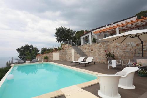a large swimming pool with chairs and a house at Il sogno di Matilde - luxury villa in Cefalù con piscina privata e panorama mozzafiato in SantʼAmbrogio