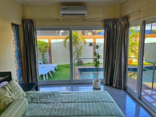 Un dormitorio con una cama y vistas a una piscina. en 2 BR villa with private swimming pool and jacuzzi 350m from beach, en Pattaya South