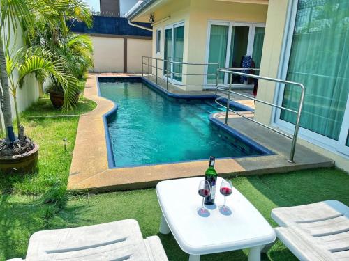 a bottle of wine sitting on a table next to a swimming pool at 2 BR villa with private swimming pool and jacuzzi 350m from beach in Pattaya South
