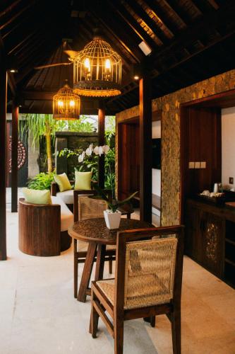 a dining room with a table and chairs and a chandelier at E Sanctuary Resort Ubud in Ubud