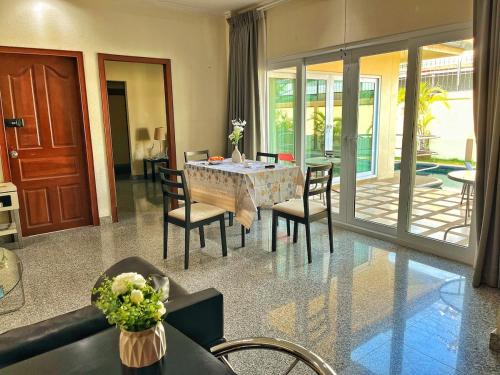 a living room with a dining room table and chairs at 2 BR villa with private swimming pool and jacuzzi 350m from beach in Pattaya South