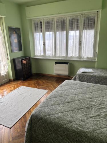 a bedroom with two beds and windows and wooden floors at GreenAppartament del lago in Viverone