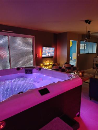 une grande baignoire dans un salon avec éclairage violet dans l'établissement Le NaturOspa spa privatif, à Le Quesnoy-en-Artois