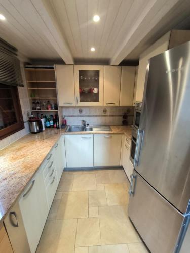 une cuisine avec des armoires blanches et un réfrigérateur en acier inoxydable dans l'établissement Very nice family cottage, à La Colmiane