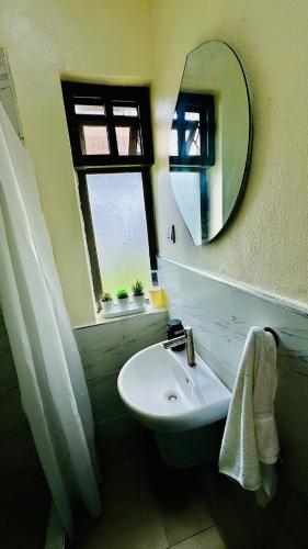 a bathroom with a sink and a mirror at HomeStay in Ikuata