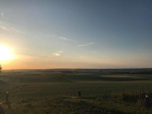 une vue d'un champ avec le coucher de soleil en arrière-plan dans l'établissement Gîte le Bellevue, à Fiennes