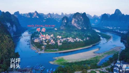 an island in the middle of a river with mountains at Yangshuo Miss Deng Colorful House in Yangshuo