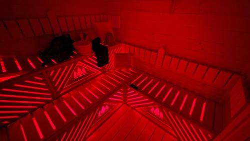 a red room with a person sitting on the stairs at Las Biala's - Domki z sauną i jacuzzi w Puszczy Noteckiej - Tylko dla dorosłych in Biala