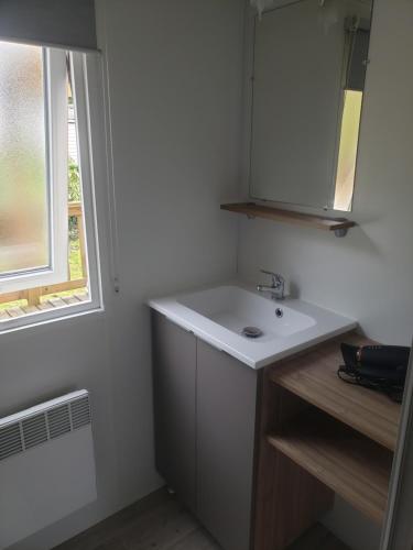 a bathroom with a white sink and a window at Mobil-home 3 chambres Pont-Aven in Pont-Aven