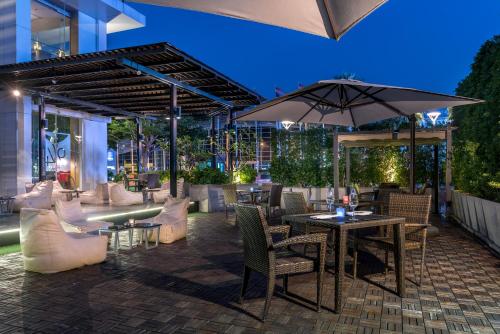 a patio with tables and chairs and an umbrella at Novotel Bangkok IMPACT in Nonthaburi