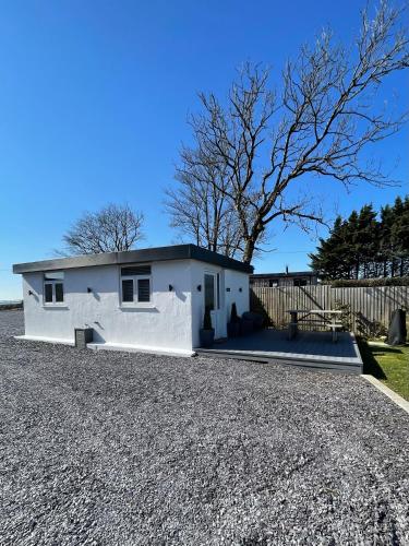 a white house on a gravel driveway at Seiriol, Modern Lodge with Games Room Access in Menai Bridge