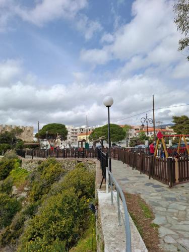 a fence next to a sidewalk with a playground at Markella's apartment Karystos in Karistos