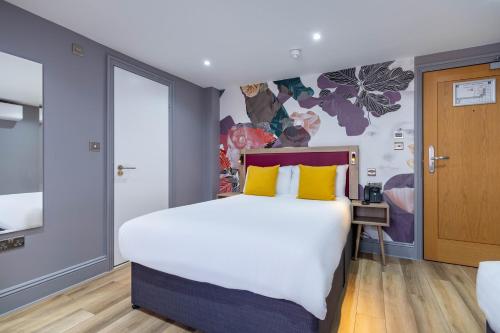 a bedroom with a large bed with yellow pillows at Comfort Inn Edgware Road W2 in London