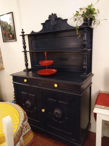 une vieille commode noire avec une plaque rouge sur elle dans l'établissement Studio l'Olivette T1, à Avignon